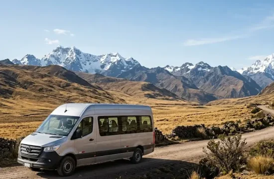A modern, well-maintained passenger van driving through a winding mountain pass toward the Palccoyo trails.