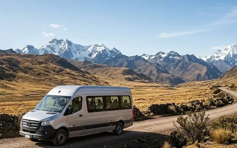 A modern, well-maintained passenger van driving through a winding mountain pass toward the Palccoyo trails.